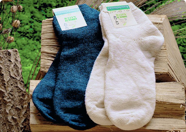 Zwei Paare dicke Hirsch Natur Socken, dunkelblau und cremefarben, auf einem Holzscheit